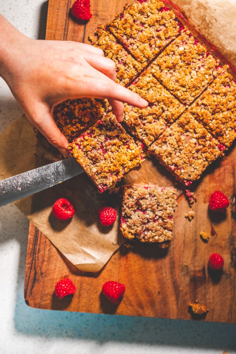 Coconut & Raspberry Flapjacks on a board - Georgie Eats