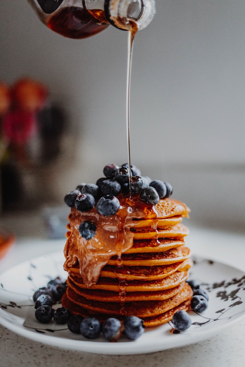 Pouring maple syrup over Vegan Pumpkin Pancakes - Georgie Eats.