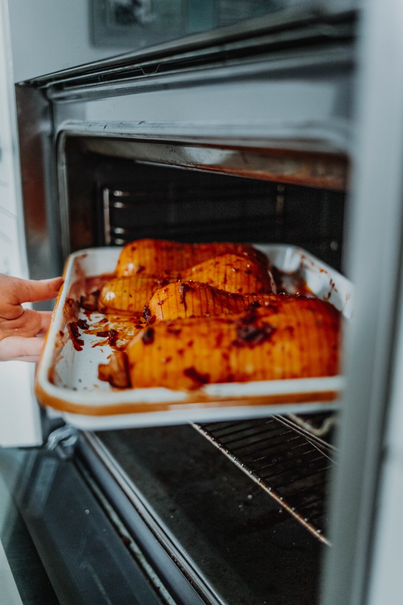 Placing the hassleback butternut squash into the oven
