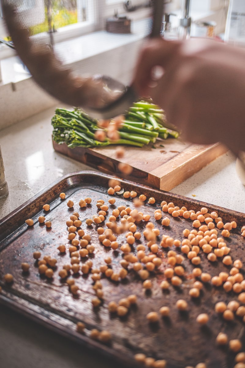pouring chickpeas onto a baking tray